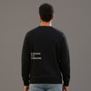 Person wearing a black sweatshirt with 'Pursuing the Unknown' text on the back against a gray background